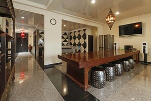 A modern kitchen with a long island, stainless steel appliances, and a decorative wall pattern. - RedDoorz Plus near Halim Perdanakusuma 2 (Jakarta)