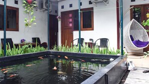 A pool with koi fish, a hanging plant, and a hanging chair. - RedDoorz Plus near Hartono Mall (Depok)