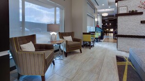 A modern lobby with seating areas, a reception desk, and large windows.