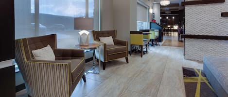 A modern lobby with seating areas, a reception desk, and large windows.