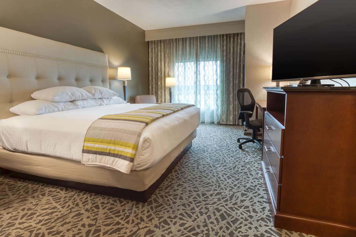 Une chambre d’hôtel avec un grand lit, deux lampes de chevet, une télévision, un bureau et une chaise.