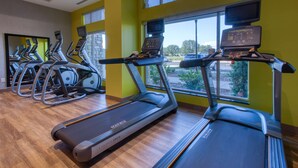 A gym with treadmills, ellipticals, and a wooden floor.