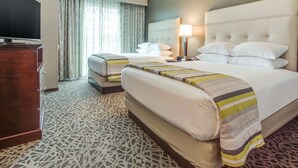 A hotel room with a large bed, a smaller bed, a TV, and a desk.