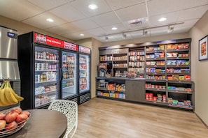 A snack and beverage section with refrigerated display cases, shelves stocked with snacks, and a coffee machine.