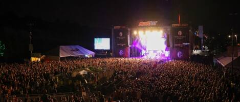 A large outdoor concert with a stage and a crowd of people.