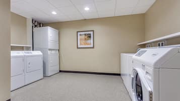 A laundry room with stacked washers and dryers, a ceiling light, and a framed picture on the wall.