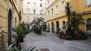 A narrow courtyard with potted plants and a cobblestone path. - COLA di Rienzo suite (Rome)