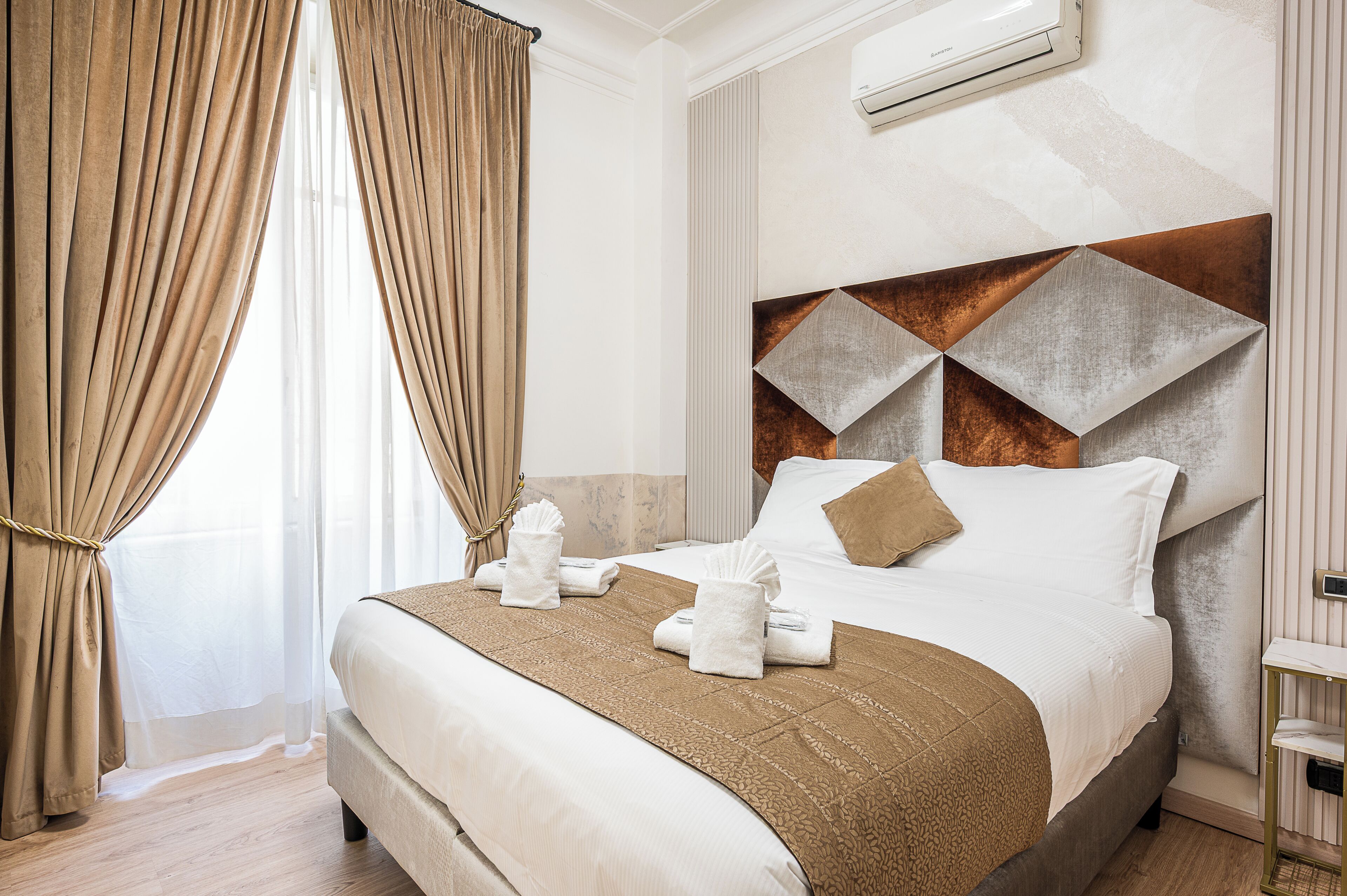 A neatly made bed with a brown bedspread, two white towels, and a brown pillow.