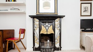 A room with a fireplace, a wooden chair, a television, and a bookshelf. - Stylish One Bedroom Flat in Vauxhall (London)