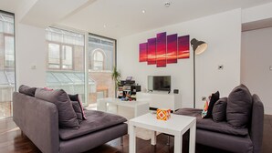 En moderne stue med to grå sofaer, et hvidt sofabord og et fladskærms-tv.