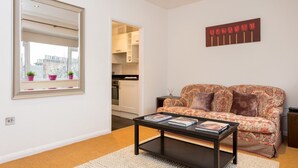 A living room with a sofa, a coffee table, a mirror, and a painting on the wall. - 1 Bedroom Flat in South Kensington (London)