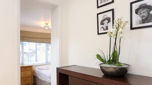 A bedroom with a bed, a wooden dresser, and a wall-mounted shelf with a potted plant. - 1 Bedroom Flat in South Kensington (London)