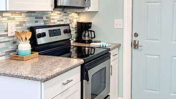 A kitchen with white cabinets, a stainless steel stove, a microwave, and a coffee maker.