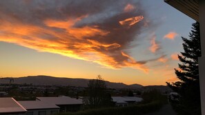 Ein Sonnenuntergang mit einer Bergkette in der Ferne und Wohnhäusern im Vordergrund.