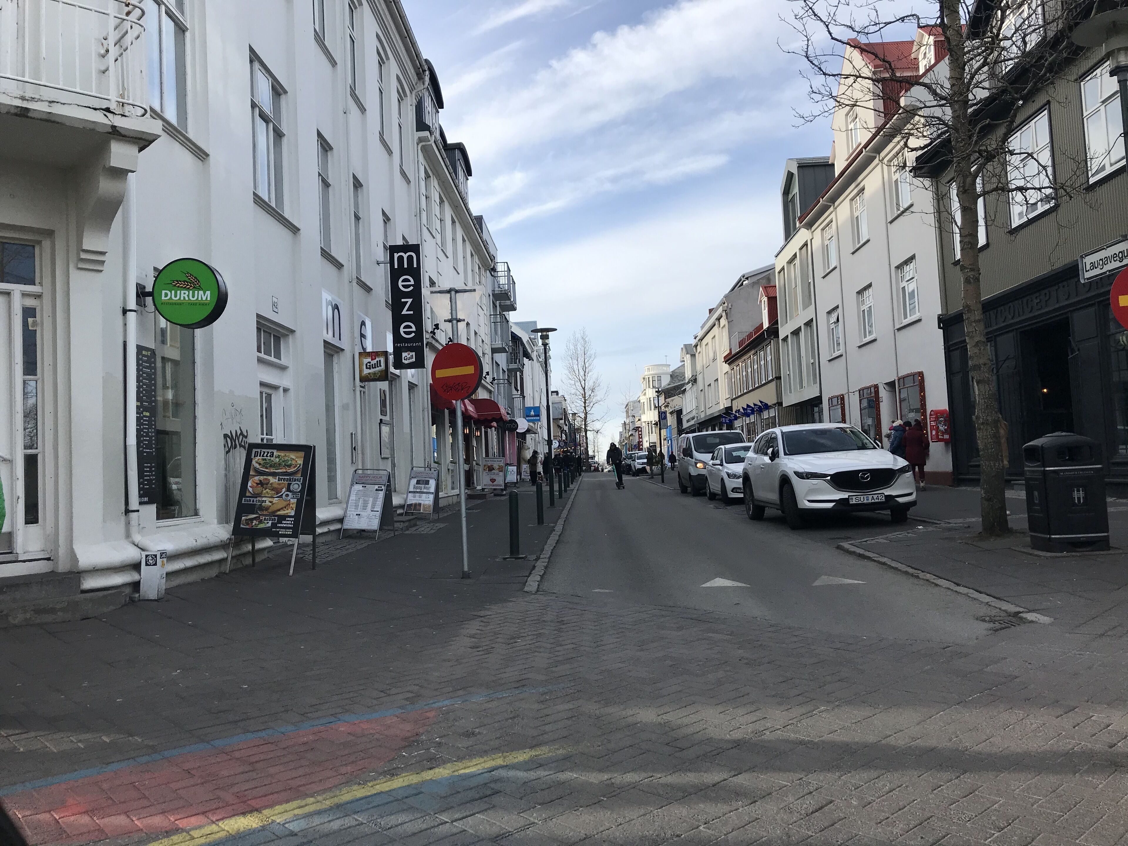 A street with buildings, a Durum restaurant sign, and parked cars.
