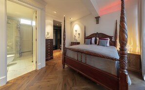 Ein geräumiges Schlafzimmer mit einem großen Himmelbett, einem hölzernen Schminktisch und einem Badezimmer mit Marmor.