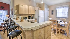 A modern kitchen with a central island, wooden cabinets, and a dining area with chairs. - Clermont Home w/ Pool & Game Room: 10 Mi to Parks! (Clermont)