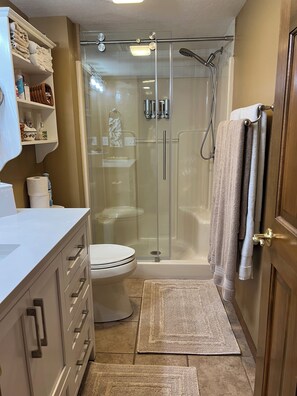 Un bany modern amb dutxa de vidre, un vàter i un moble de bany amb calaixos i un lavabo.
