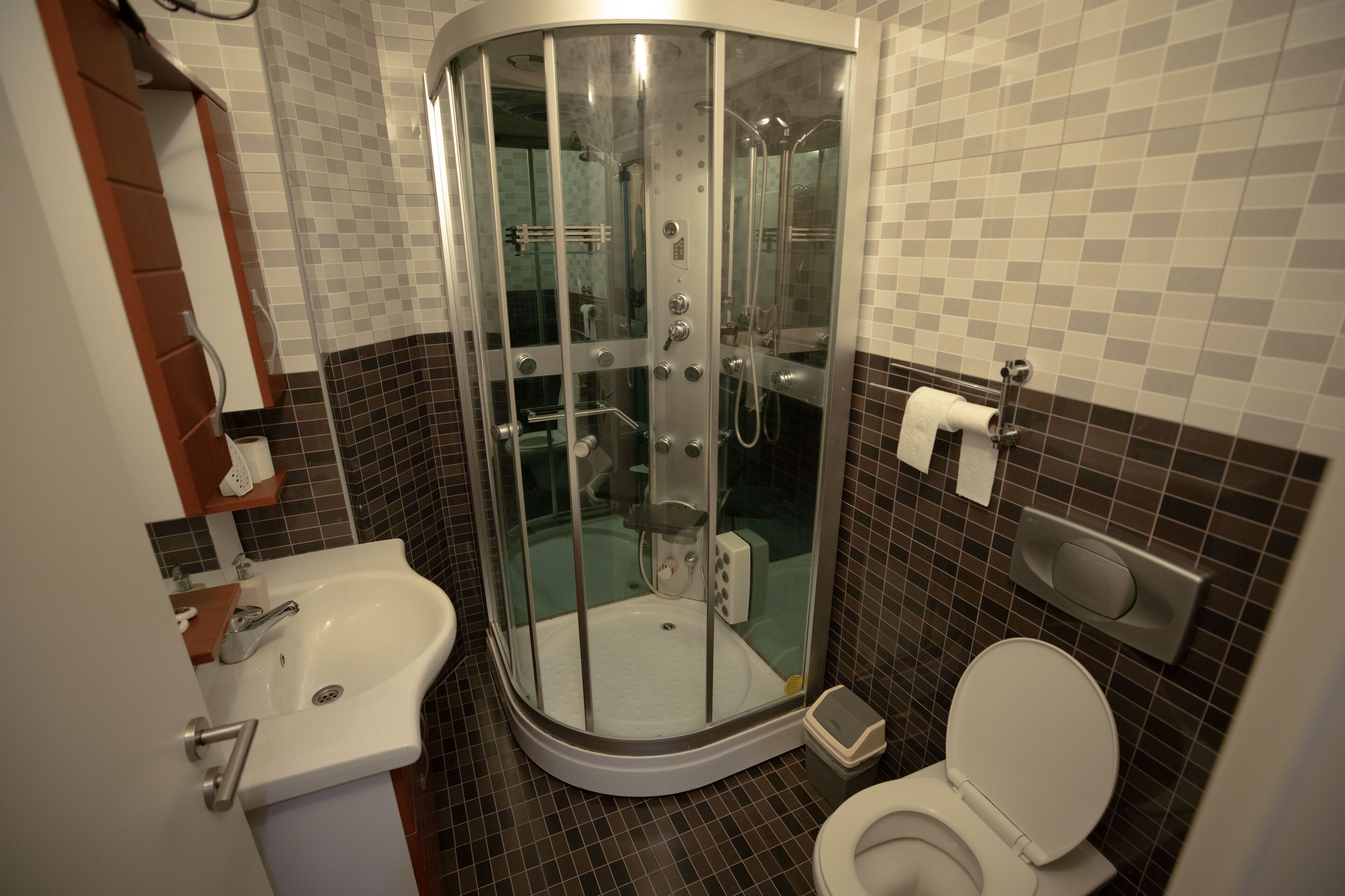 A bathroom with a glass-enclosed shower, a sink, and a toilet.