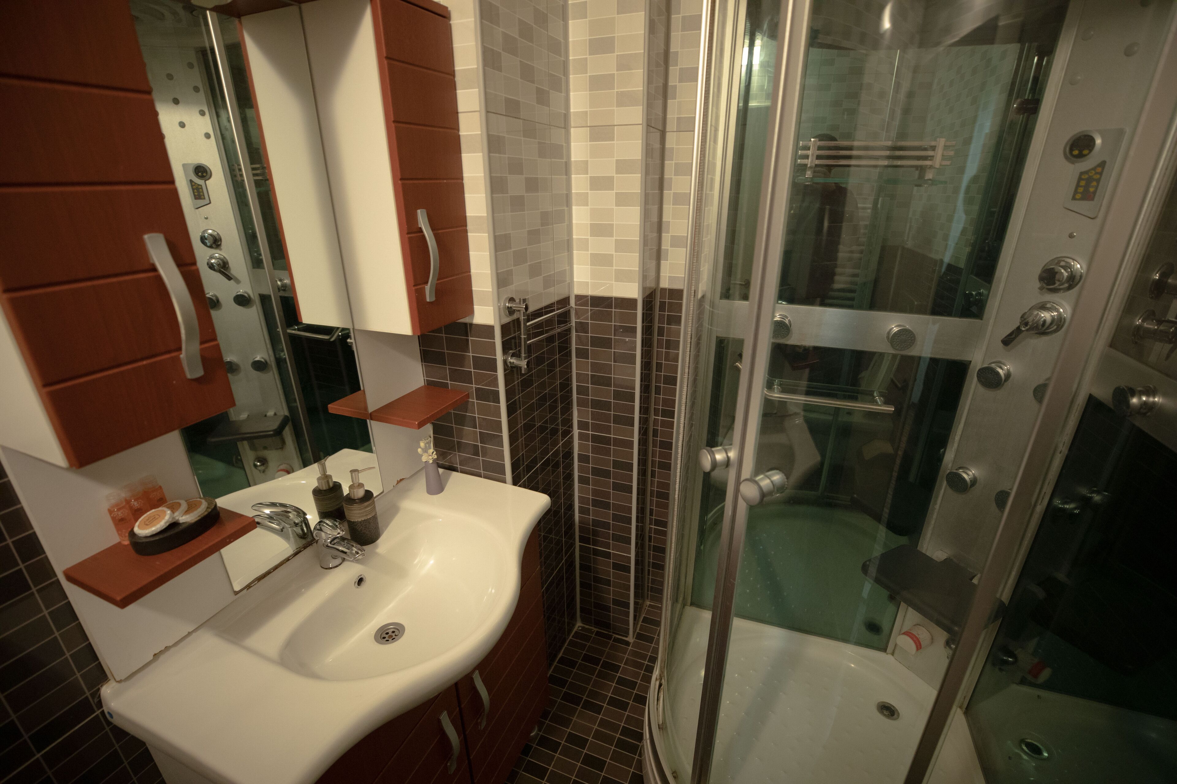 A bathroom with a white sink, a mirror, a glass-enclosed shower, and tiled walls.