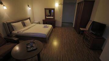 A hotel room with a bed, bedside table, TV, and a mirror.