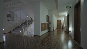A spacious hallway with a wooden floor, a staircase, and a wooden door at the end. - Hotel Denis & Spa (Pristina)