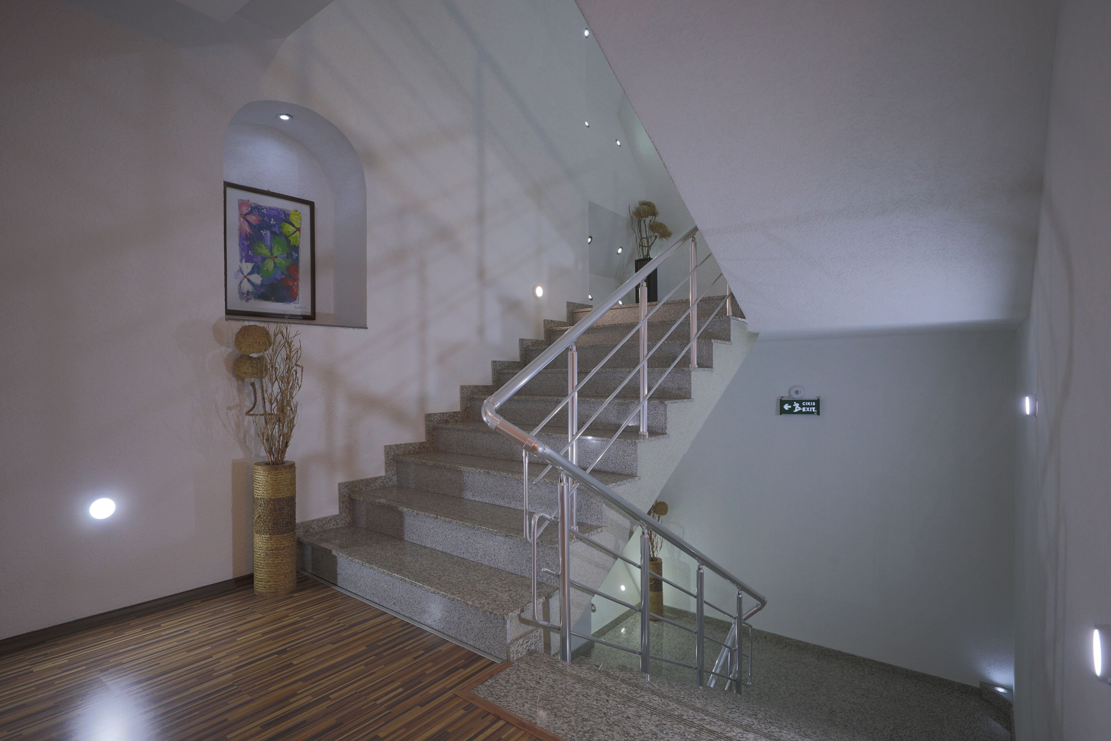 A modern interior with a staircase, a framed artwork, and a decorative vase.