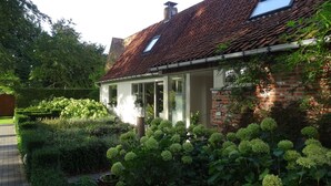 A house with a tiled roof, a glass door entrance, and a brick wall. - A great place to see Bruges, Ghent and the coast of Flanders (Oostkamp)