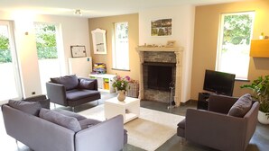 A modern living room with grey sofas, a fireplace, a television, and a bookshelf. - A great place to see Bruges, Ghent and the coast of Flanders (Oostkamp)