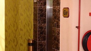A hotel lobby with a marble elevator, a red carpet, and a wall with a 'GF' sign indicating a gender-neutral bathroom. - Hotel Grand Palace Ampang (Ampang)