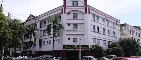 A multi-story hotel with a prominent sign reading "Hotel Grand Palace."
