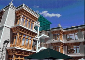 A multi-story building with traditional architectural features, including wooden balconies and large windows. - Hotel Om Ladakh (Leh)