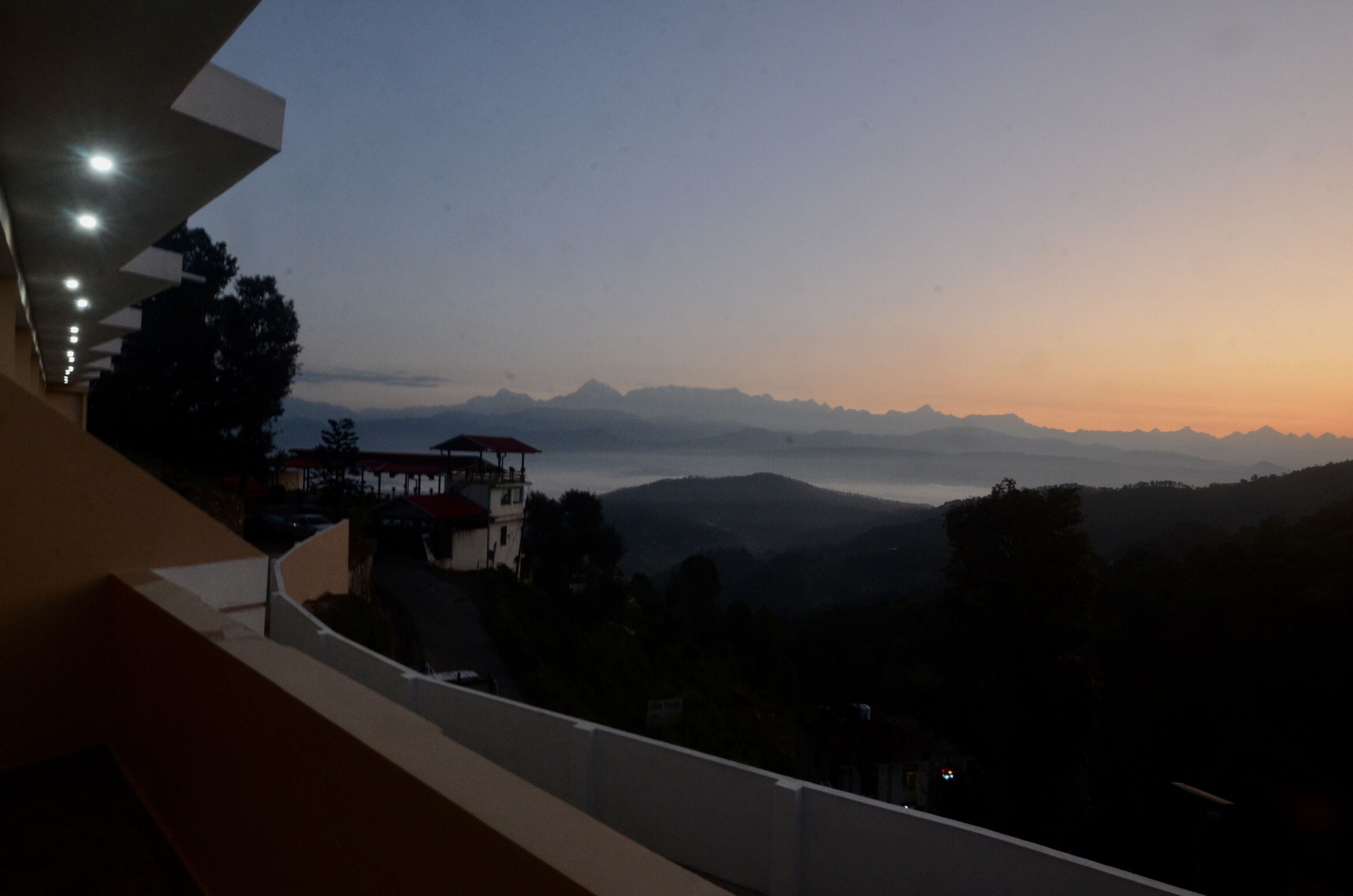 Un balcon donnant sur un paysage montagneux au coucher du soleil.