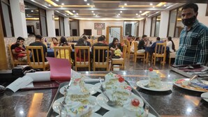 A dining area with tables set for meals, featuring a tray with cake slices and plates. - Uttarakhand Resort (Somashwar)