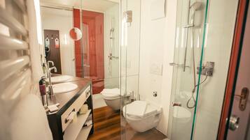 Un baño moderno con ducha envuelta en vidrio, tocador de madera y un inodoro independiente.