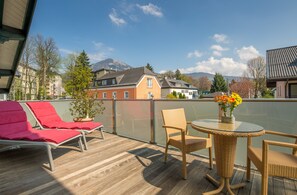 A balcony with wicker furniture, a glass table, and a potted plant. - Hotel Rosenvilla (Salzburg)