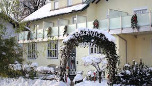 A hotel entrance with a snow-covered archway, a balcony with railings, and a sign that reads "ROSENVILLA HOTEL". - Hotel Rosenvilla (Salzburg)