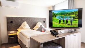 A modern hotel room with a bed, bedside table, TV, and a small desk area. - Hotel Rosenvilla (Salzburg)