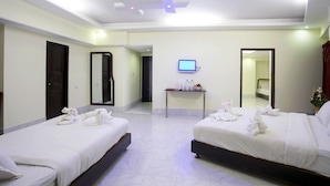 A hotel room with two beds, a television on the wall, and a small table with toiletries. - Panshi Inn (Sylhet)