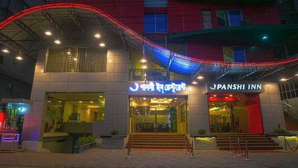 A hotel with a modern facade, featuring a prominent entrance with glass doors and a staircase leading to the lobby. - Panshi Inn (Sylhet)