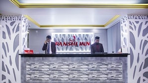 A reception desk at Panshi Inn with a stone-patterned backdrop and a modern design. - Panshi Inn (Sylhet)