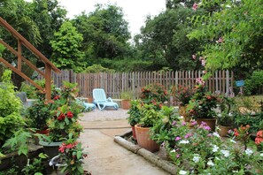 A garden with a wooden deck, potted plants, and a blue chair.