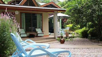 Uma casa com varanda, área de estar externa e um jardim.