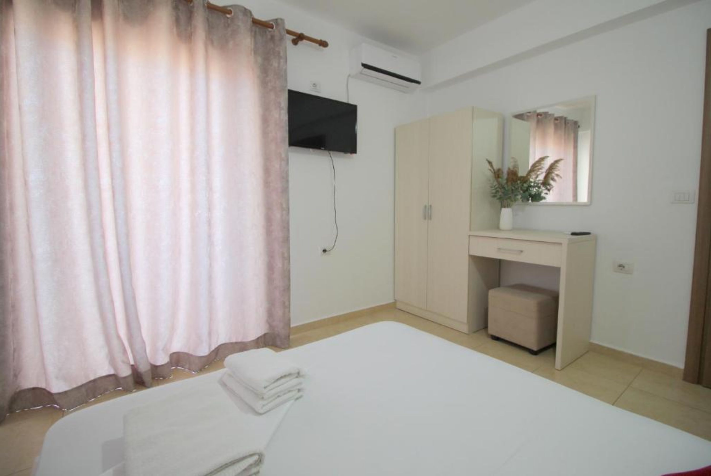 A bedroom with a bed, a wardrobe, a mirror, and an air conditioning unit.