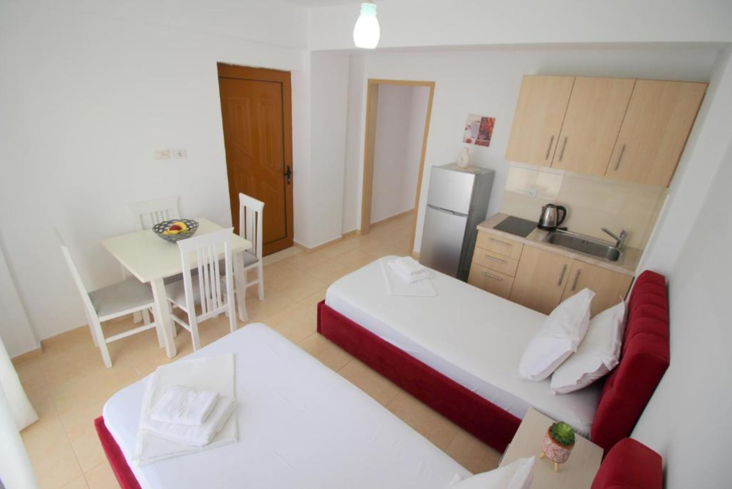 A compact room with a bed, a small dining table, a kitchenette, and a separate seating area.