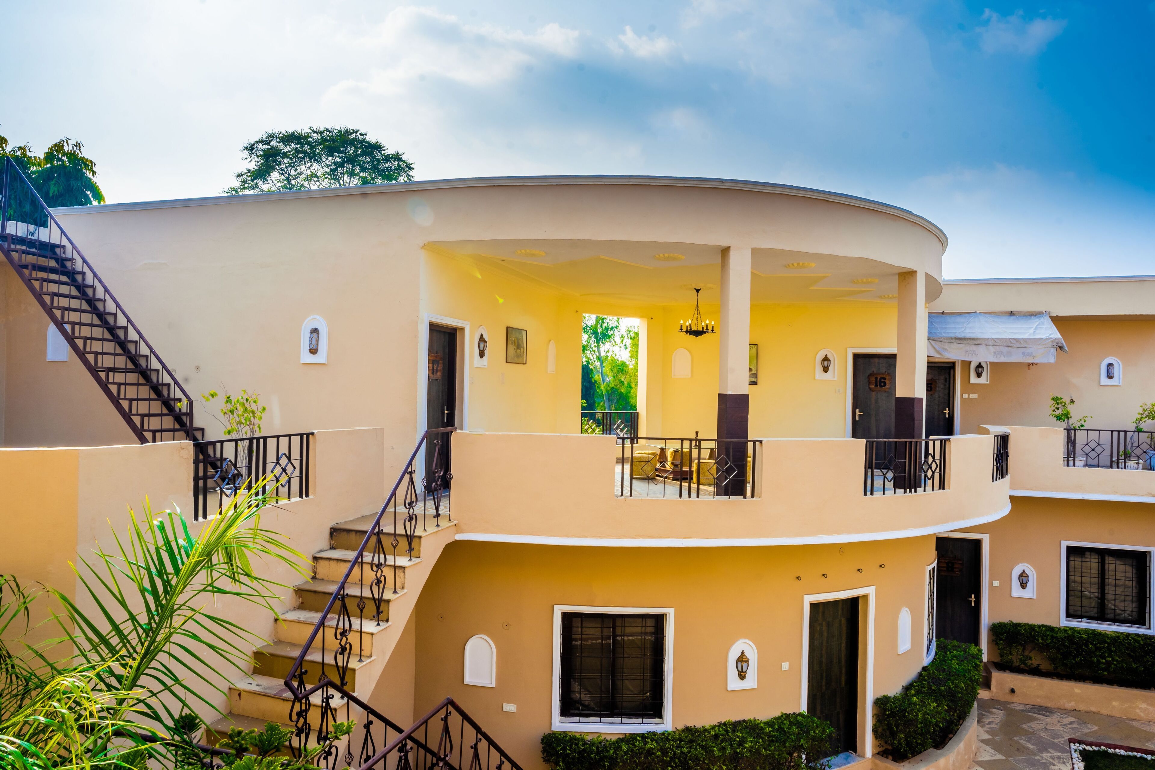 Un edificio de varios pisos con fachada curva, una escalera y un balcón con mobiliario exterior.