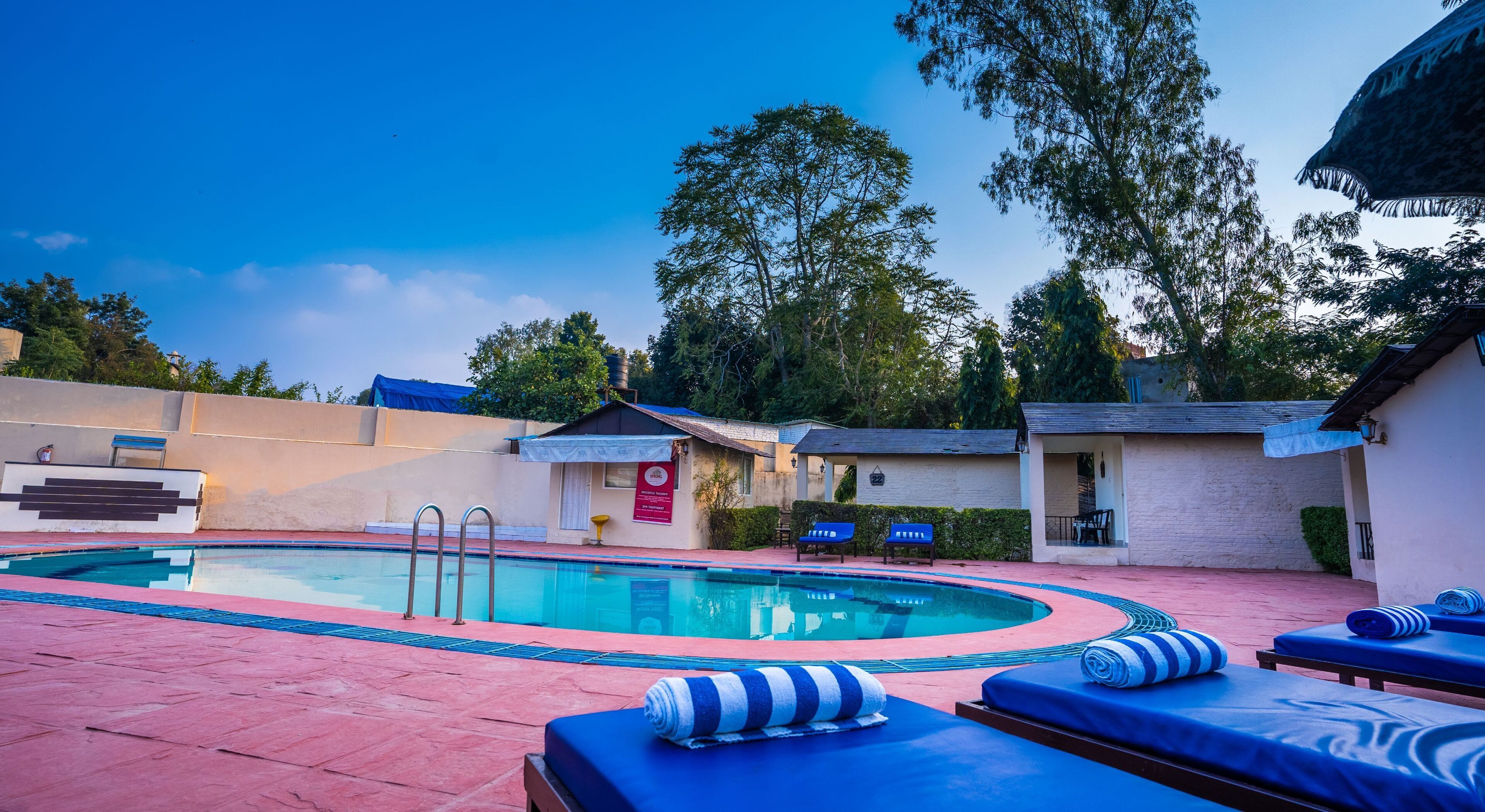 Una piscina con lettini e un piccolo edificio con un cartello.