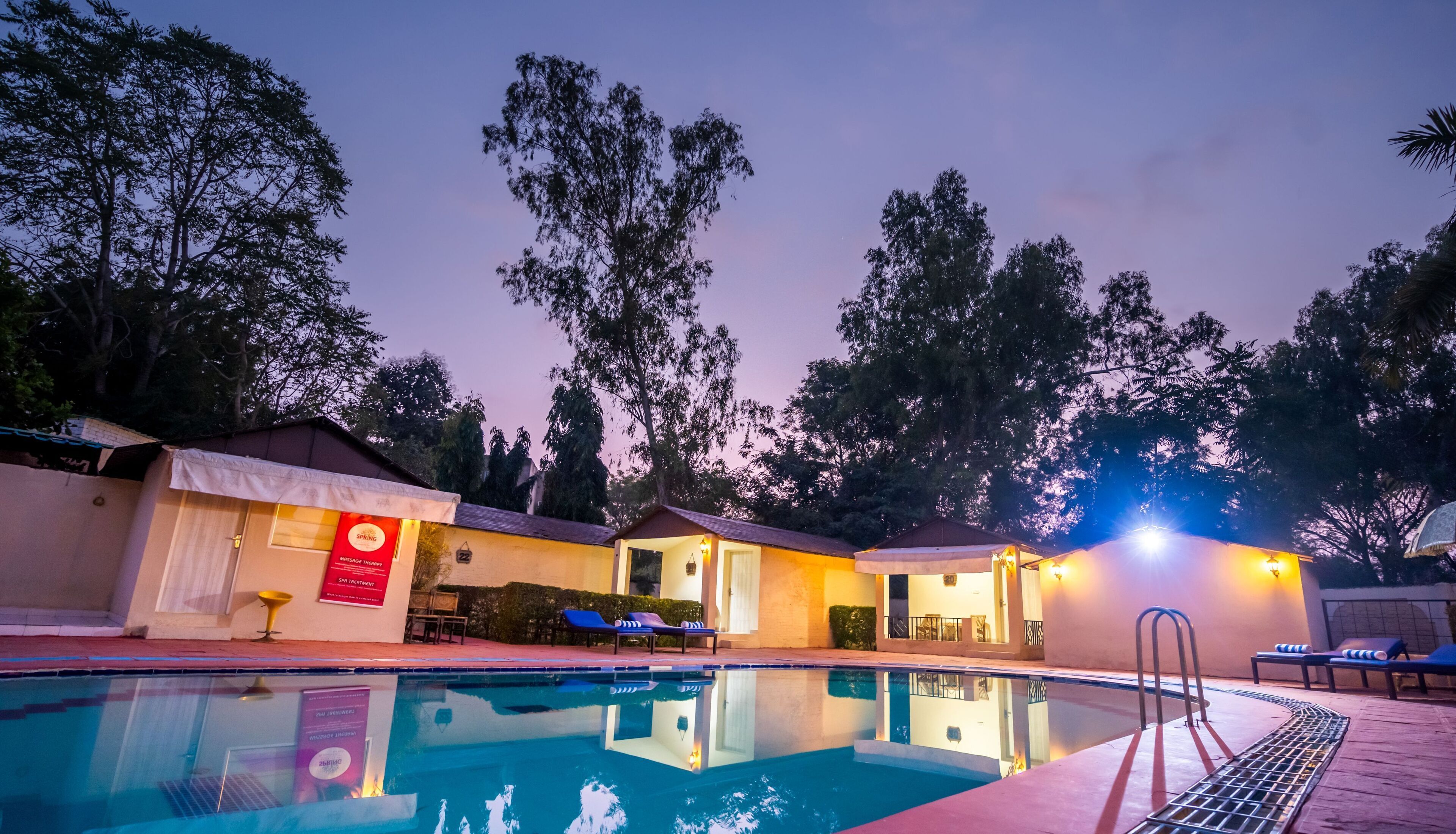 Ein Poolbereich mit Liegestühlen und einem Gebäude mit Spa-Angeboten.