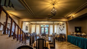 A spacious dining area with a high ceiling, chandeliers, and a view through large windows. - Shani Vilas - Ranthambore (Sawai Madhopur)