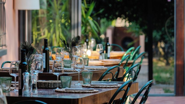 A dining table set with wine glasses, water glasses, and cutlery, surrounded by chairs. - Trere Agriturismo (Faenza)